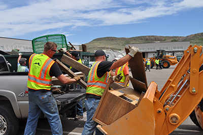 City workers help unload a truck of debris for Community Pride Days.